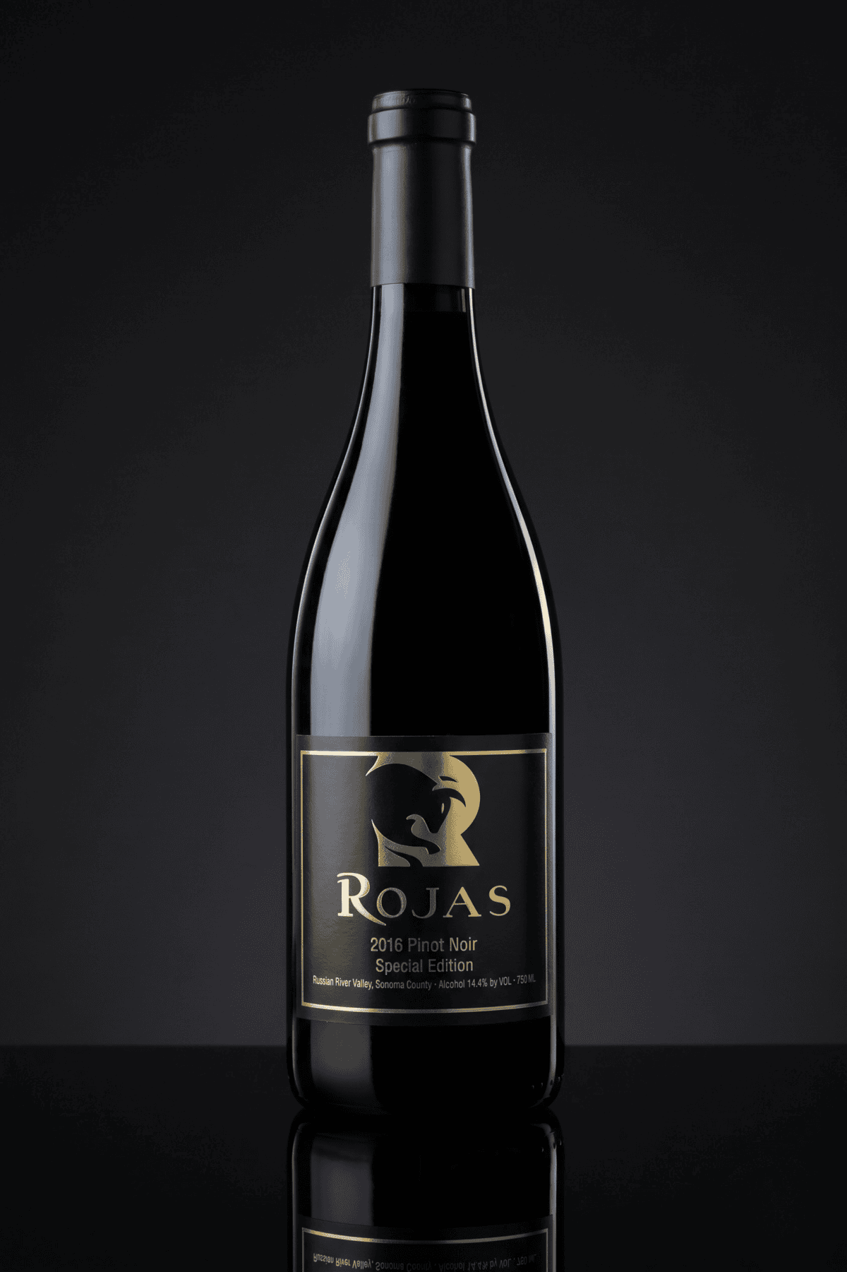 A bottle of Rojas 2016 Pinot Noir Special Edition wine with a black and gold label, displayed upright against a dark, reflective background.