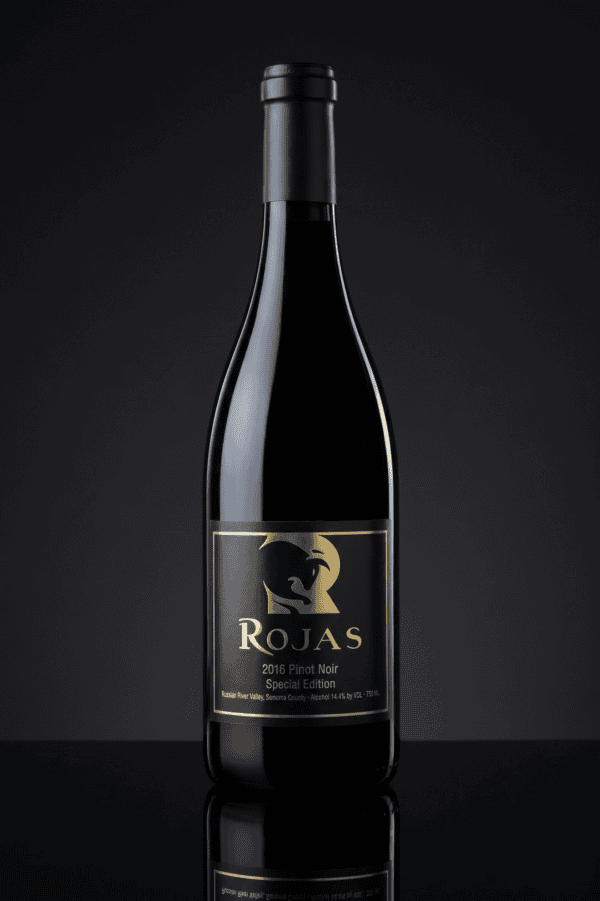 A bottle of Rojas 2016 Pinot Noir Special Edition wine with a black and gold label, displayed upright against a dark, reflective background.