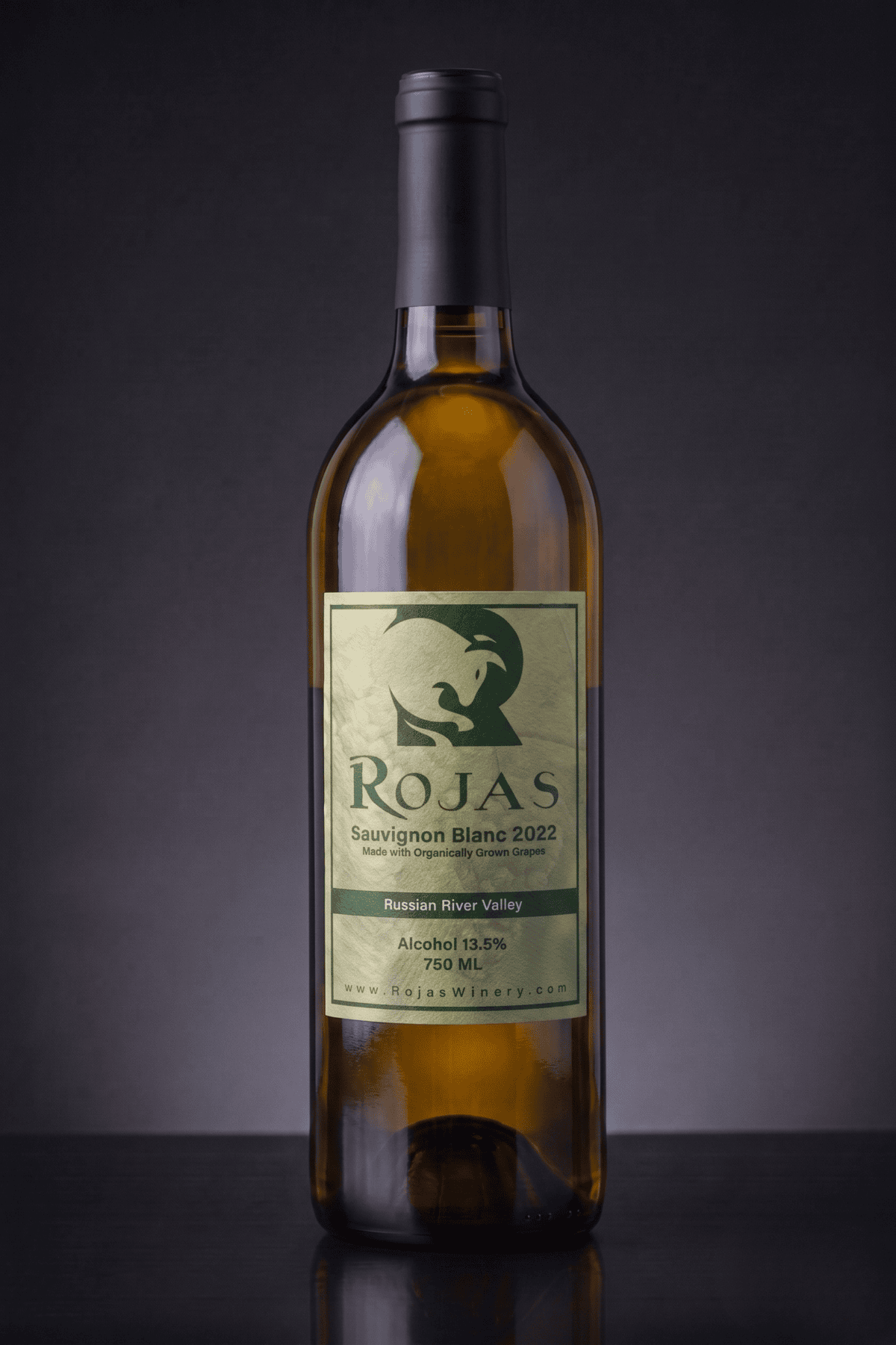 A bottle of Rojas Sauvignon Blanc 2022 wine with a greenish label stands upright on a dark gray background. The label displays the winerys logo and wine details.
