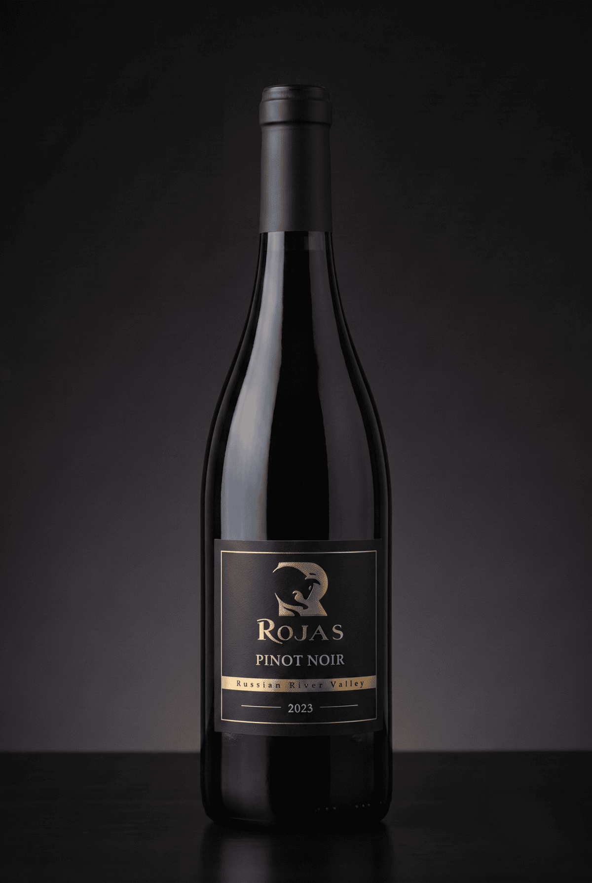 A bottle of Rojas Pinot Noir wine, vintage 2023, with a black and gold label, set against a dark, gradient background.