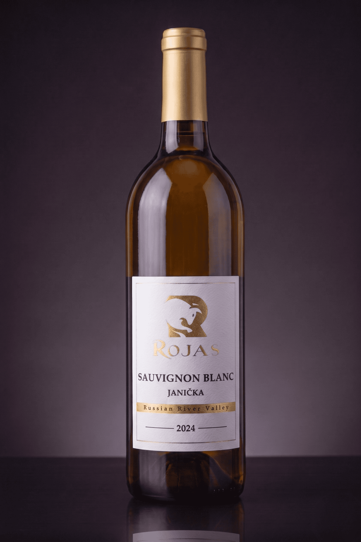 A bottle of Rojas Sauvignon Blanc Janíčka wine from the Russian River Valley, vintage 2024, stands upright against a dark, gradient background.