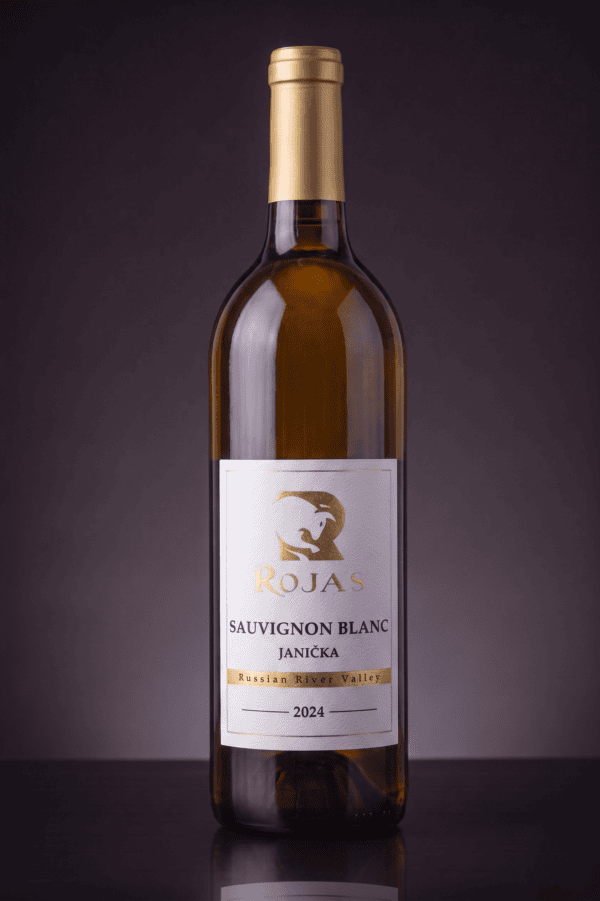 A bottle of Rojas Sauvignon Blanc Janíčka wine from the Russian River Valley, vintage 2024, stands upright against a dark, gradient background.